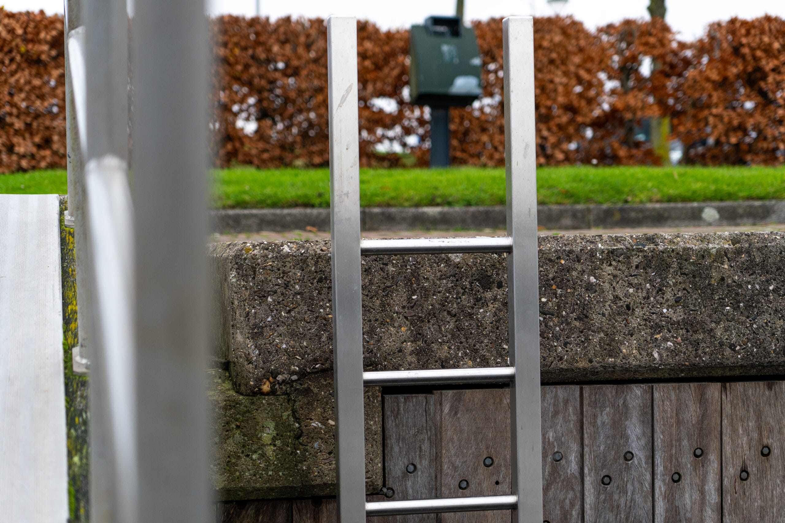 RVS Veiligheidsladder stevig gemonteerd aan een betonnen steiger voor veilige toegang tot het water.