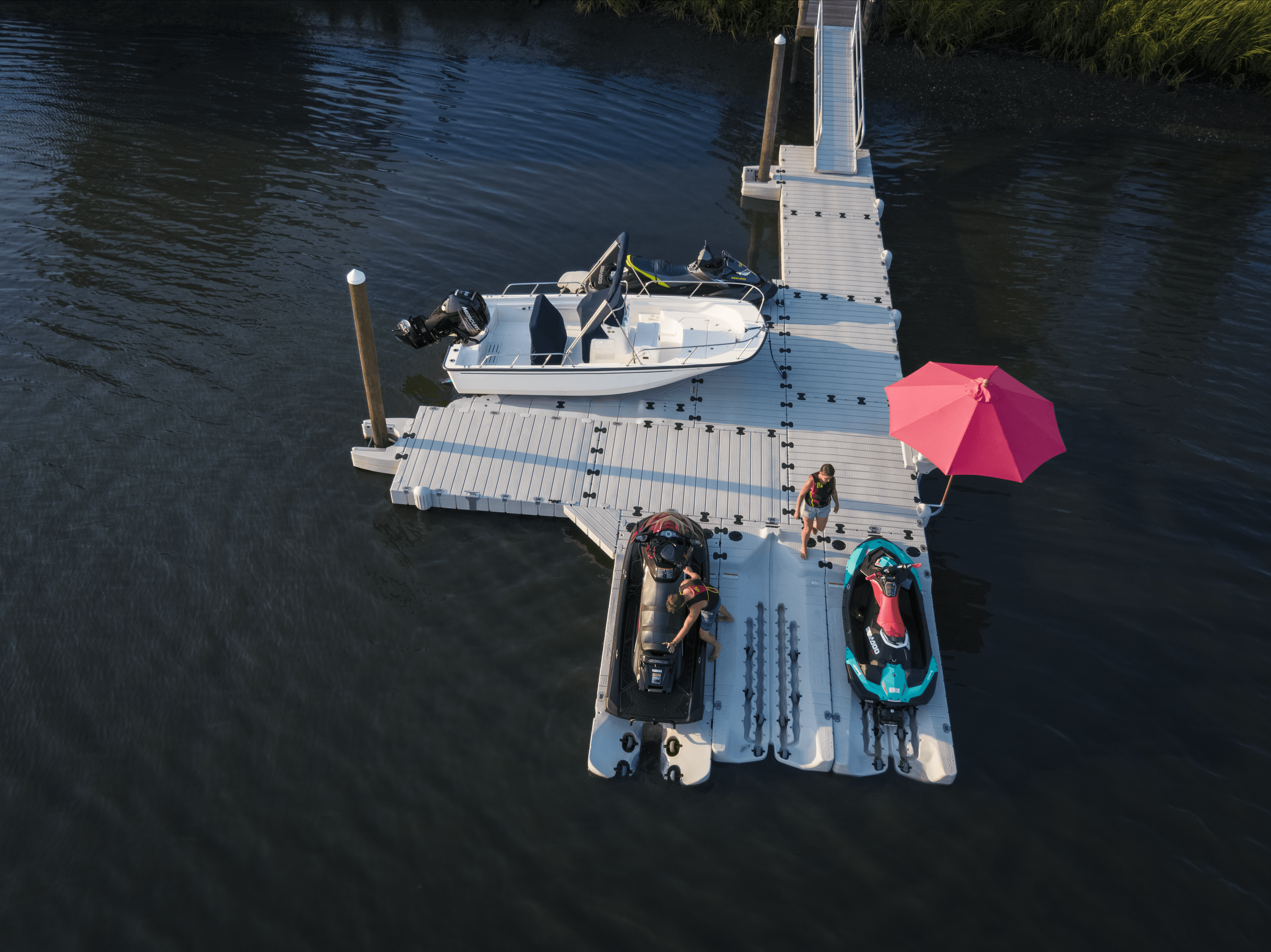Luchtfoto van EZ Dock kunststof drijvende steiger met aangemeerde boot en twee waterscooters met mensen aan het water