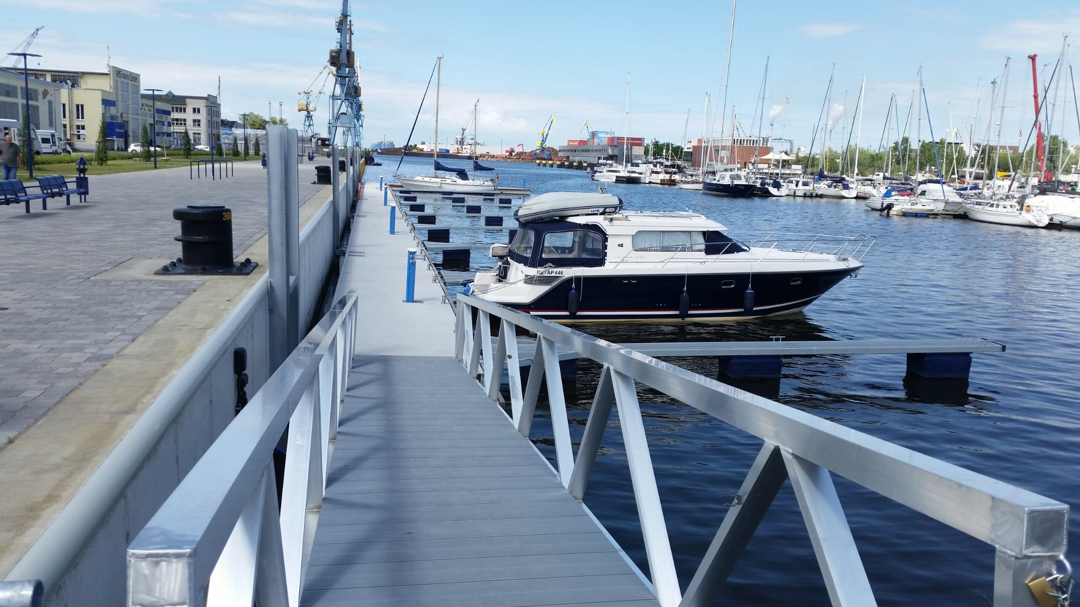 Aluminiumweg mit Handläufen, die in einem Yachthafen verwendet werden, verbunden mit schwimmenden Gerüsten.