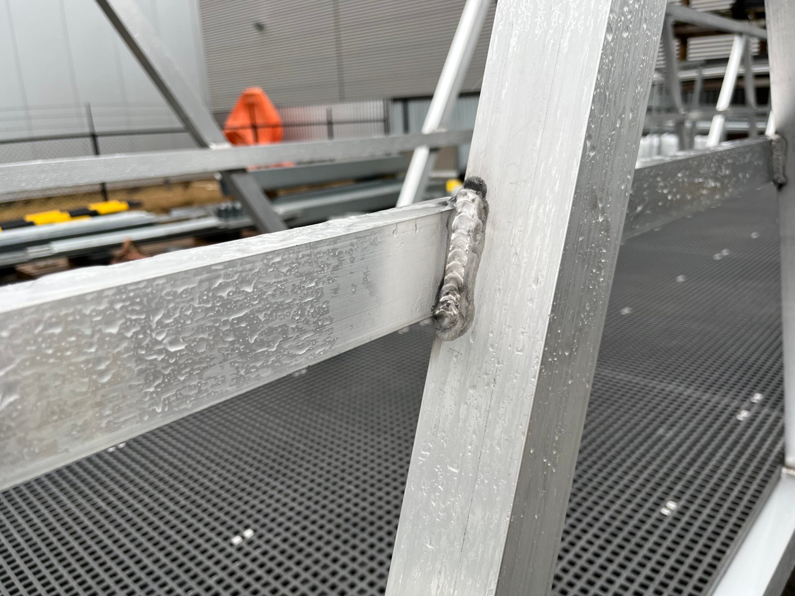 Detail of an aluminum walkway with water droplets on a metal surface.