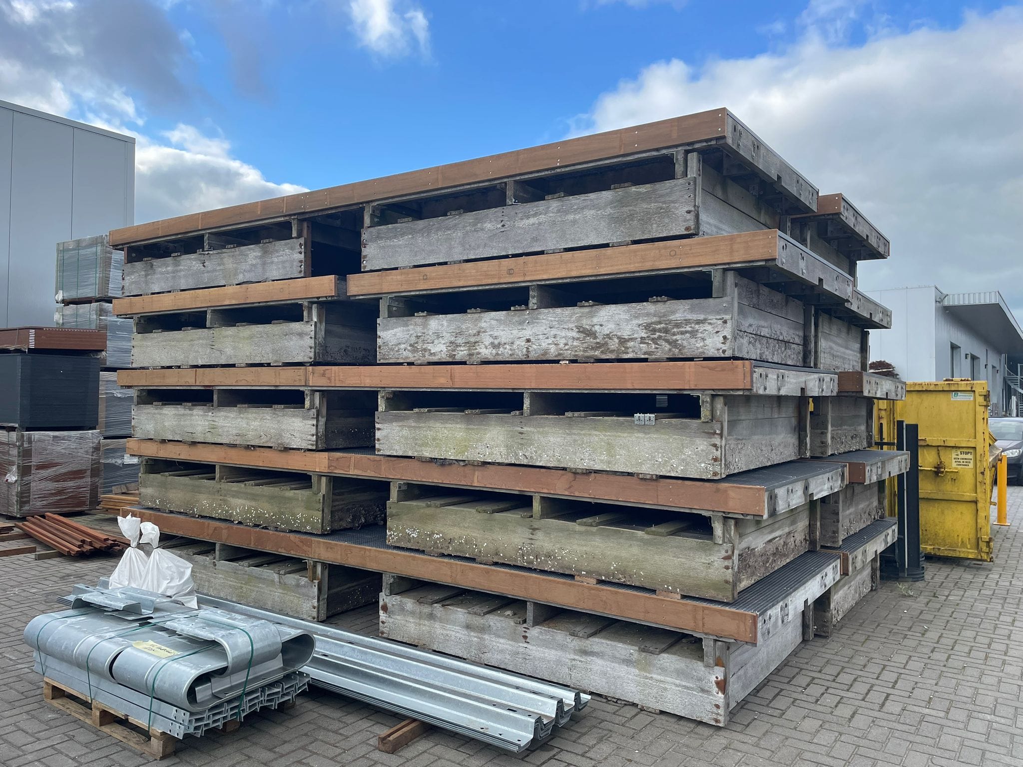  Gestapelde gebruikte houten steigerdelen op het terrein van Havenspecialist, klaar voor hergebruik in duurzame steigerconstructies.
